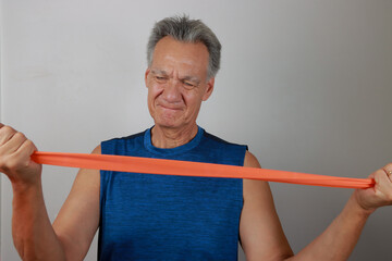 Mature Man at home using a fitness Rubber band or Stretch Bands for increase mobility  