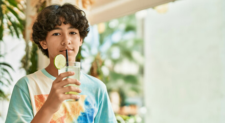 Fototapeta premium Asian young teen enjoying lime drink in bright outdoor setting