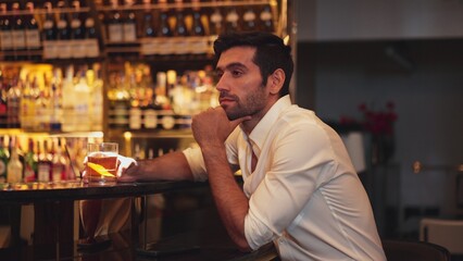 Smart man in white shirt drinking cocktail Old fashioned waiting friends or couple while chatting on smartphone in special party beverage vibrant at nightclub on Friday meeting night time. Vinosity.