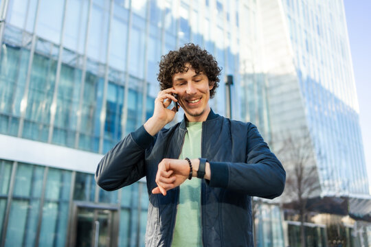 Businessman using smartphone and smartwatch in cityscape