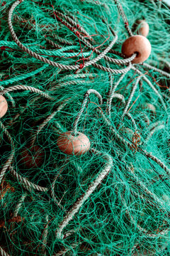 Intricate textures in a fishing net with wooden buoy