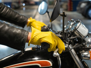 Close-up of hands in yellow leather gloves holding the steering wheel of a motorcycle