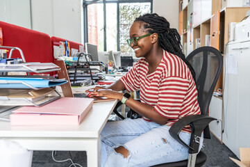 In a vibrant office environment, a black female activist works on her computer, focusing on education, culture, human rights, and race equality, contributing to positive change.	
