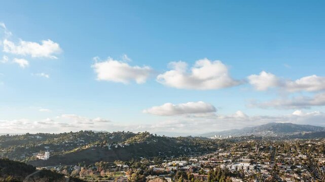 Landscape time lapse of clouds over small town with rolling Hills behind and blue skies