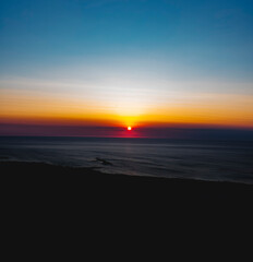 Obraz premium The sun at orange sunset just above the surface of the sea