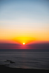 The sun at orange sunset just above the surface of the sea