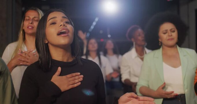 Women passionately singing and worshiping during church service, showcasing spirituality and faith, in a diverse community standing together in prayerful unity