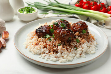 Delicious rice with meatballs, sauce and green onions on white table, closeup