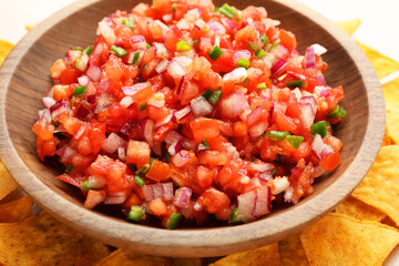 Delicious salsa in bowl and nacho chips on table, closeup