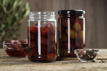 Pickled olives and spices on wooden table, closeup