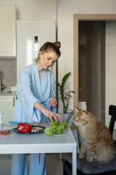 Woman in Kitchen Preparing Food with Curious Cat Nearby