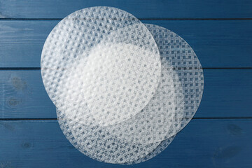 Edible rice paper sheets on blue wooden table, flat lay