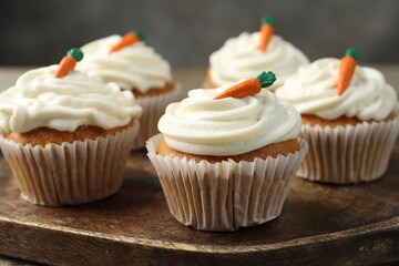 Delicious carrot cupcakes on wooden board, closeup