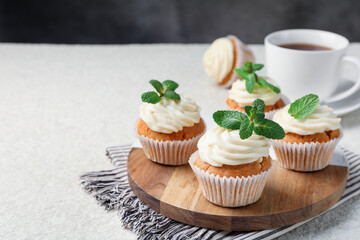 Delicious carrot cupcakes with mint on light textured table, closeup. Space for text