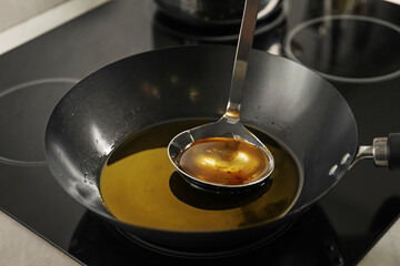 Used cooking oil and ladle in frying pan on stove, closeup