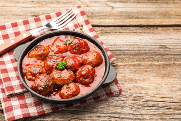 Delicious meatballs with tomato sauce in baking dish on wooden table, closeup. Space for text