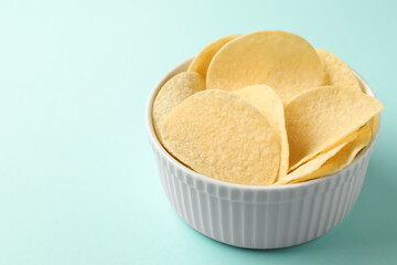 Tasty potato chips on light blue background, closeup. Space for text