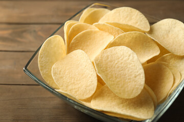 Tasty potato chips on wooden table, closeup