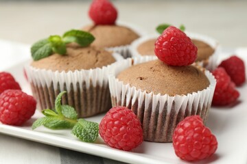 Delicious muffins with raspberries and mint on table, closeup