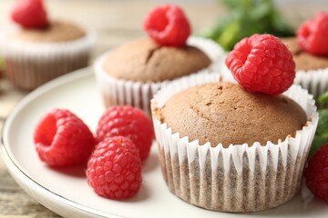 Delicious muffins with raspberries and mint on wooden table, closeup