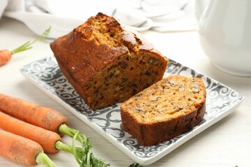 Homemade carrot cake with nuts and vegetables on white wooden table, closeup