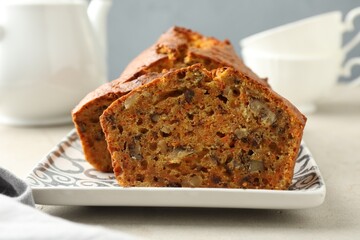 Cut homemade carrot cake with nuts on light grey table, closeup