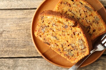Pieces of homemade carrot cake with nuts and fork on wooden table, top view. Space for text