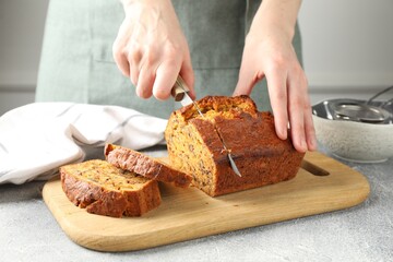 Woman cutting homemade carrot cake at grey table, closeup