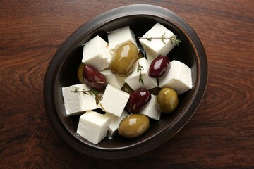 Marinated olives with feta cheese and rosemary on wooden table, top view
