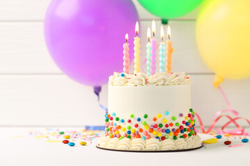 Delicious bento cake with colorful sprinkles and burning candles on white table, closeup. Space for text