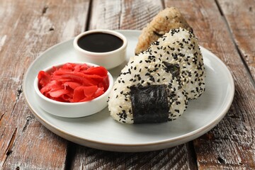 Rice balls (onigiri), soy sauce and pickled ginger on wooden table, closeup. Traditional Japanese dish