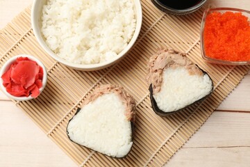 Tasty onigiri (Japanese rice balls) with tuna served on wooden table, flat lay