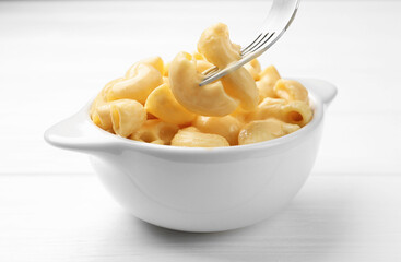 Eating delicious macaroni and cheese at white wooden table, closeup