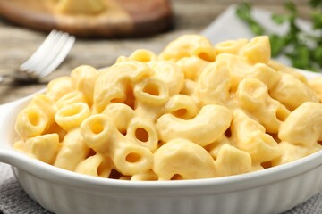 Delicious pasta with cheese sauce in baking dish on table, closeup