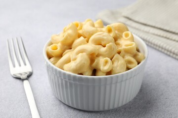 Delicious pasta with cheese sauce and fork on grey table, closeup