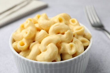 Delicious pasta with cheese sauce and fork on grey table, closeup