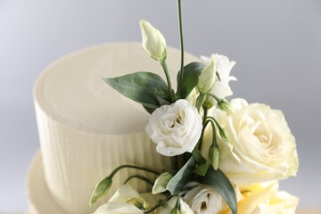 Delicious wedding cake decorated with flowers on grey background, closeup
