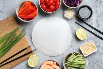 Rice paper sheets and different ingredients on light grey table, flat lay