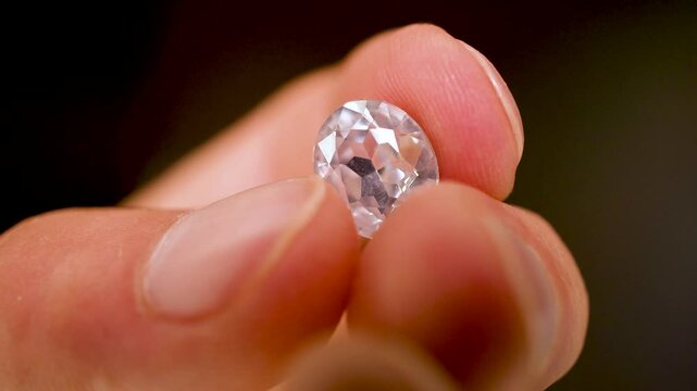 Gemstones on a white table in multicolor illumination, A man's hand holds the jewels.
