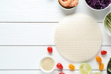 Rice paper sheets and different ingredients on white wooden table, flat lay. Space for text