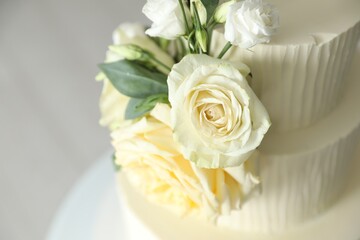 Delicious wedding cake with floral decor on blurred background, closeup