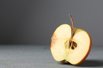 Half of overripe apple on grey wooden table, closeup. Space for text