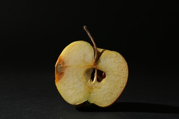 Half of overripe apple on black background, closeup