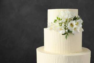Delicious wedding cake with floral decor on grey background, closeup. Space for text