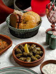 Grape dolma in ceramic pot, bread, empty glass