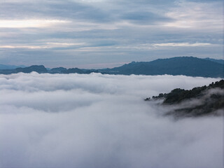 Fototapeta premium An wide Aerial view of a mountainous landscape with green fields and a village in the foreground. The mountain dominates the background, partially covered by clouds. Tana Toraja - Indonesia 