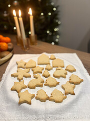A festive arrangement of holiday cookies on a table, with candles and Christmas decorations