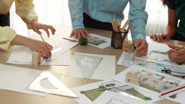 A video of architect use measurement tools and pencil to measure blueprint. Architect design house construction on a table at studio, with architectural plan scattered around. Focus hand. Delineation.