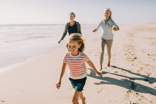 Multigenerational family having fun and walking on a sandy beach together