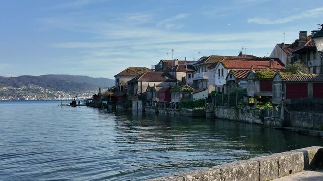 Traditional galician granaries, known as horreos, stand on stilts by the water's edge, topped with stone crosses in combarro, spain